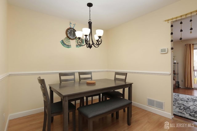 dining room with visible vents, baseboards, an inviting chandelier, and wood finished floors