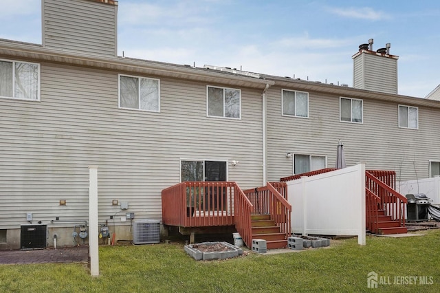 back of property with central air condition unit, a yard, and a chimney