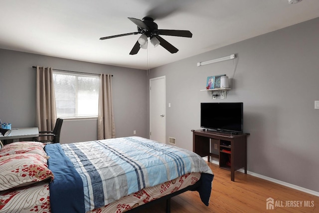 bedroom featuring visible vents, baseboards, light wood-style floors, and a ceiling fan