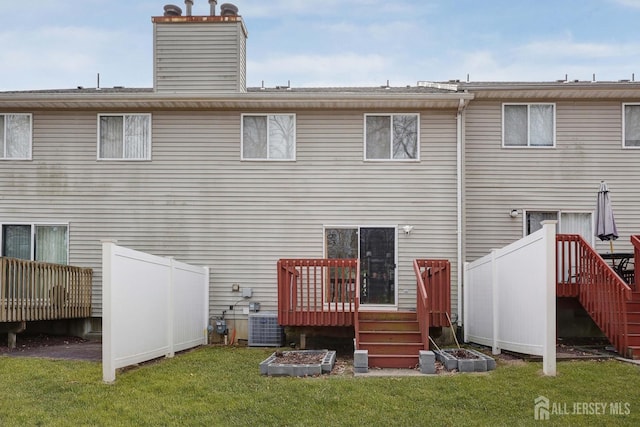 rear view of property with a wooden deck, a lawn, central AC, and a chimney