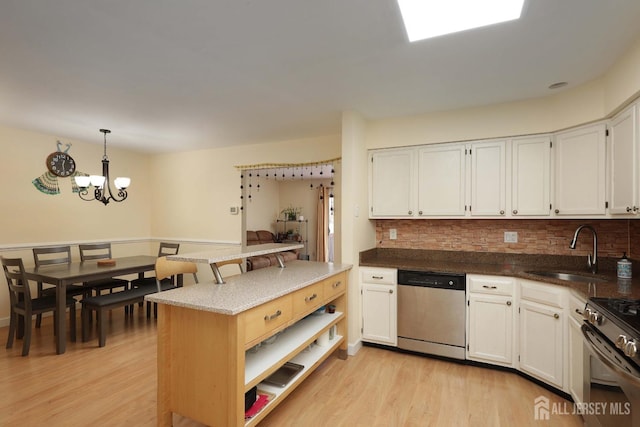 kitchen with hanging light fixtures, stainless steel appliances, light wood-type flooring, and a sink