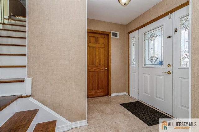 foyer with stairway, light tile patterned flooring, visible vents, and baseboards