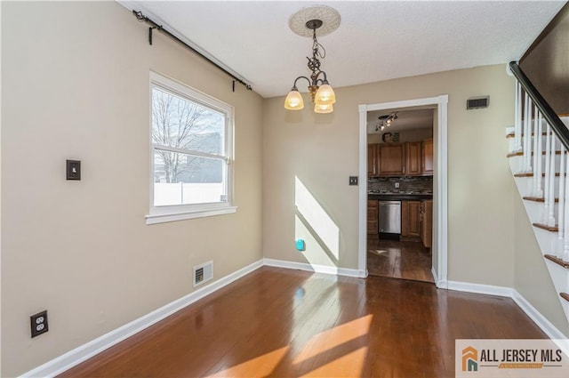 unfurnished dining area featuring stairway, dark wood-style flooring, visible vents, and baseboards