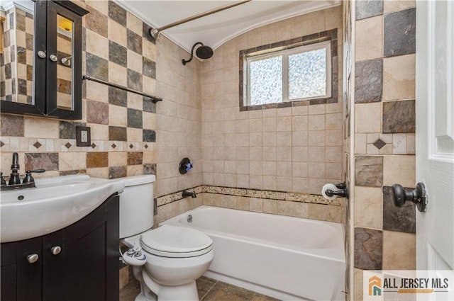 bathroom with toilet, tub / shower combination, vanity, and tile walls