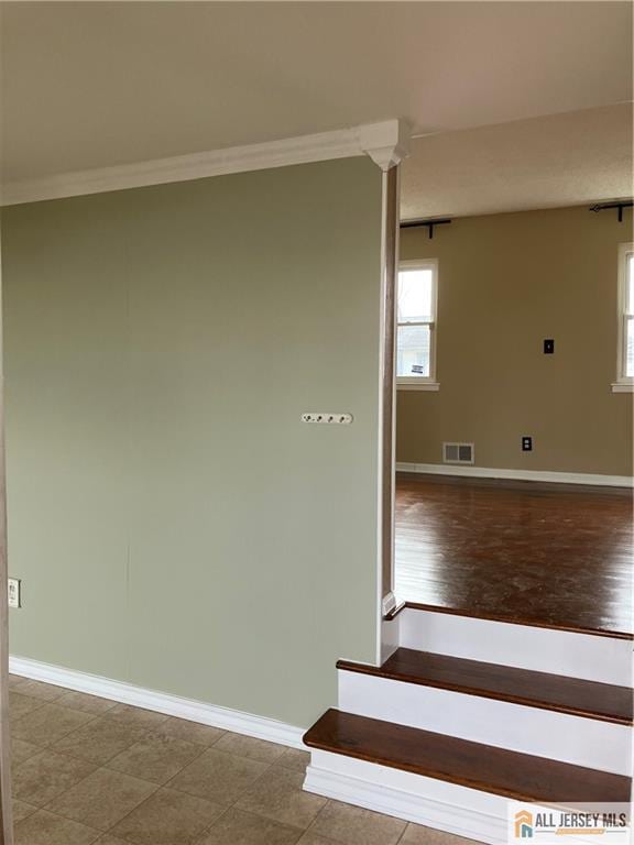 stairway with visible vents, a healthy amount of sunlight, baseboards, and ornamental molding