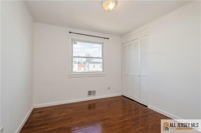 unfurnished bedroom featuring wood finished floors, visible vents, baseboards, a closet, and crown molding