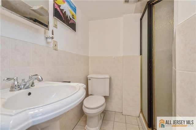 bathroom featuring tile walls, a sink, a shower stall, and tile patterned floors