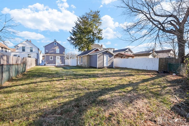 view of yard with a shed, a residential view, a fenced backyard, and an outdoor structure