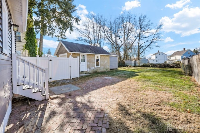 back of property with stone siding, a lawn, an outdoor structure, and a fenced backyard