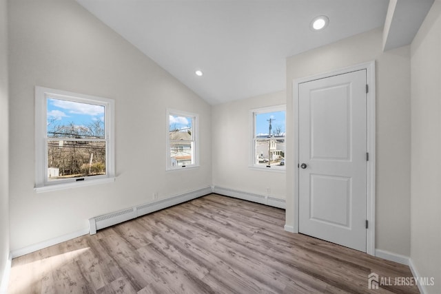 interior space with baseboards, lofted ceiling, light wood-style flooring, baseboard heating, and recessed lighting