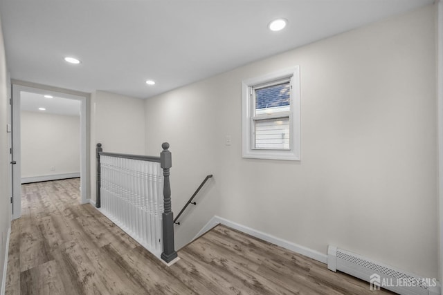 corridor with a baseboard radiator, recessed lighting, an upstairs landing, baseboards, and light wood finished floors