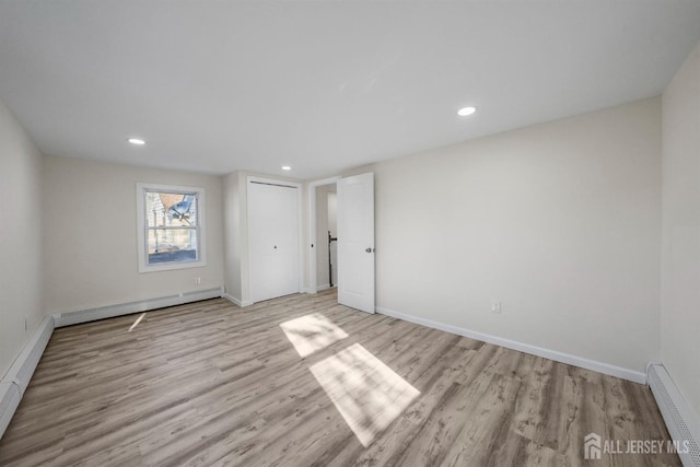 unfurnished bedroom featuring light wood-type flooring, baseboards, and baseboard heating