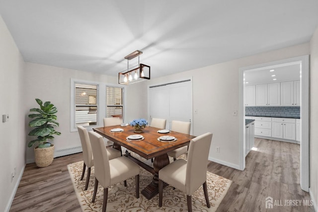 dining area featuring baseboard heating, light wood-style flooring, and baseboards