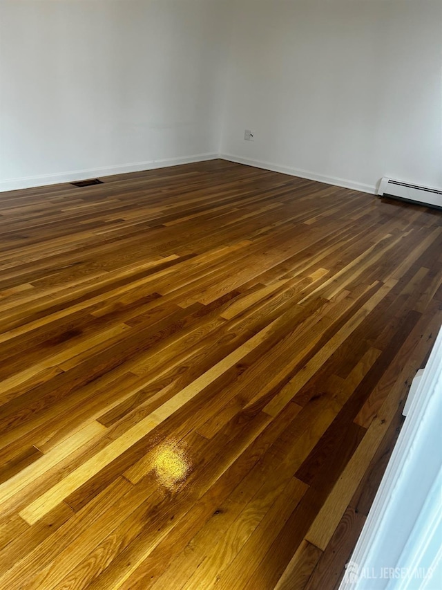 24 Kensington Ave, Old Bridge, NJ 08857 - spare room featuring baseboard heating, dark wood finished floors, and baseboards