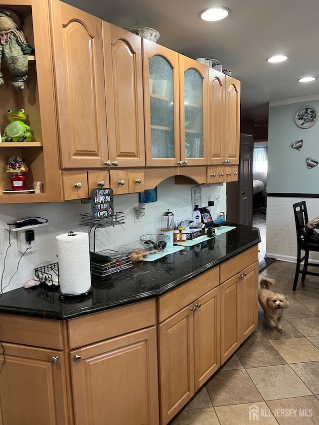 kitchen with light tile patterned floors, tasteful backsplash, crown molding, and dark stone countertops