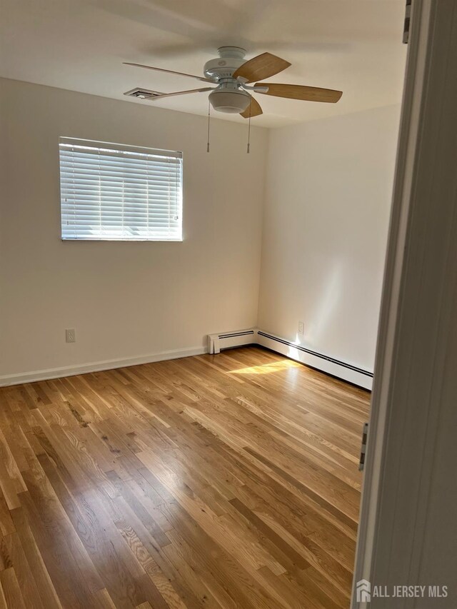 24 Kensington Ave, Old Bridge, NJ 08857 - spare room with a ceiling fan, wood finished floors, baseboards, and a baseboard heating unit