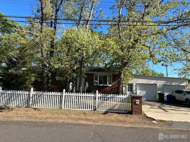 24 Kensington Ave, Old Bridge, NJ 08857 - view of front of home with an attached garage, a fenced front yard, concrete driveway, and brick siding