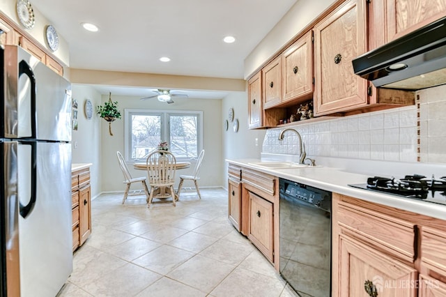 kitchen with under cabinet range hood, a sink, black dishwasher, freestanding refrigerator, and light countertops