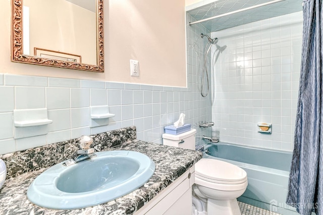 bathroom featuring a wainscoted wall, toilet, vanity, shower / bath combo with shower curtain, and tile walls