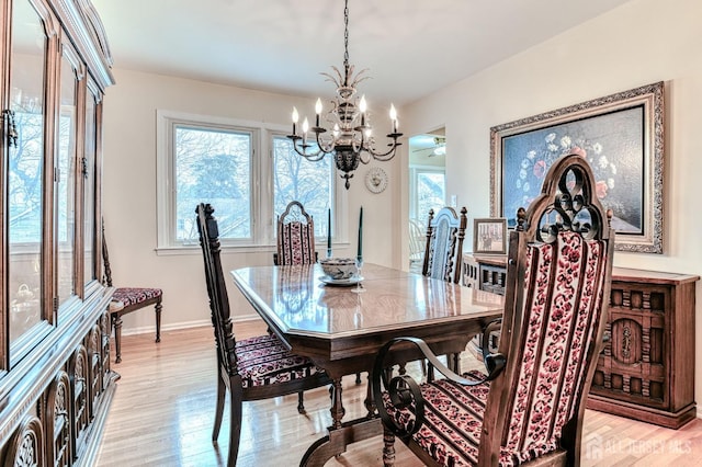 dining space with light wood-style floors, baseboards, and a chandelier