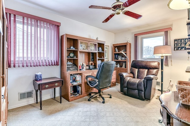 carpeted home office featuring a ceiling fan, visible vents, and baseboards