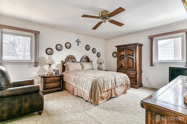 bedroom with light colored carpet and a ceiling fan