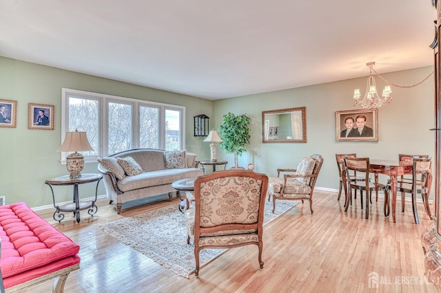 living area featuring an inviting chandelier, baseboards, and light wood-type flooring