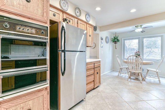 kitchen with a ceiling fan, freestanding refrigerator, double oven, light countertops, and light tile patterned floors