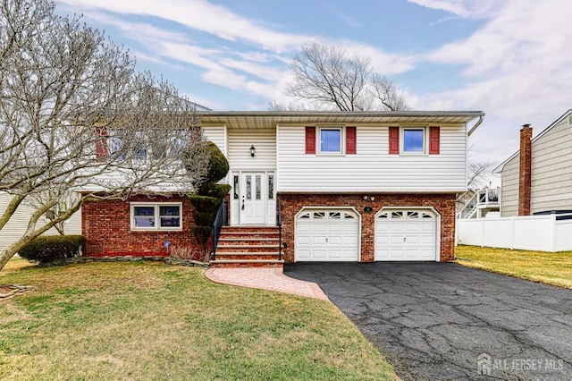 split foyer home featuring aphalt driveway, an attached garage, fence, and a front lawn