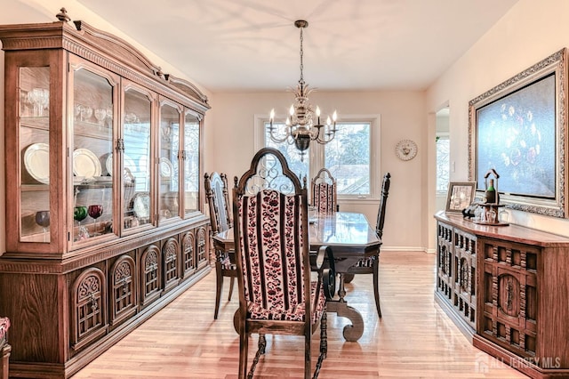 dining space with an inviting chandelier, baseboards, and light wood-type flooring