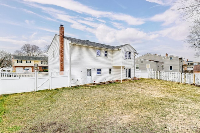 rear view of house with a lawn, a fenced backyard, and a chimney