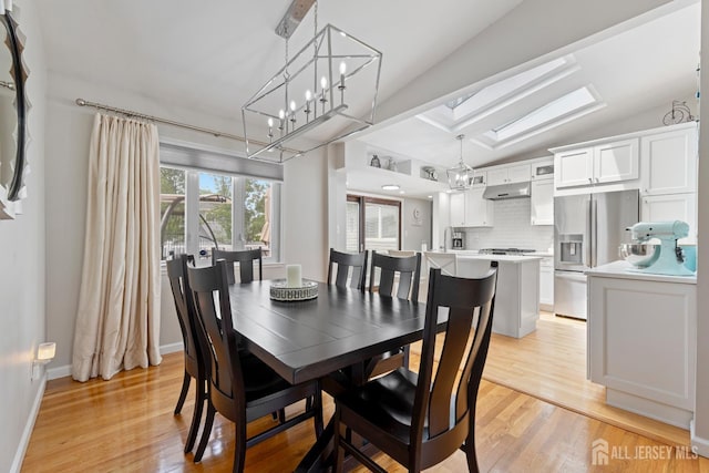 27 York St, Old Bridge, NJ 08857 - dining space featuring light wood finished floors, vaulted ceiling, a chandelier, and a skylight