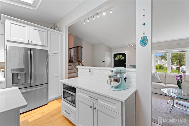 27 York St, Old Bridge, NJ 08857 - kitchen featuring appliances with stainless steel finishes, track lighting, decorative backsplash, white cabinetry, and lofted ceiling