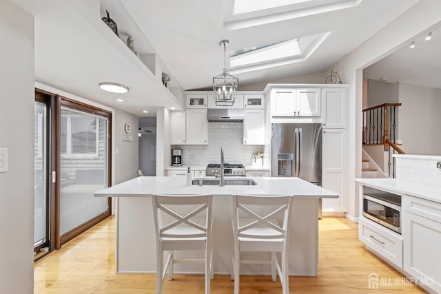 27 York St, Old Bridge, NJ 08857 - kitchen featuring stainless steel appliances, decorative backsplash, light wood finished floors, white cabinets, and vaulted ceiling