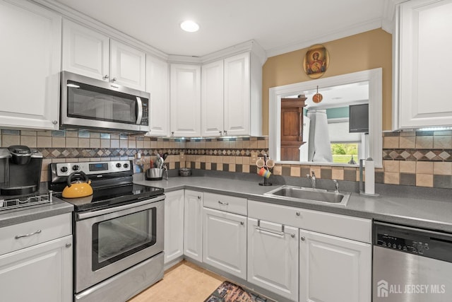 kitchen featuring stainless steel appliances, a sink, white cabinetry, backsplash, and dark countertops