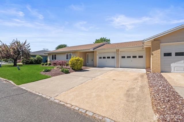 view of front of home featuring an attached garage, driveway, a front yard, and brick siding