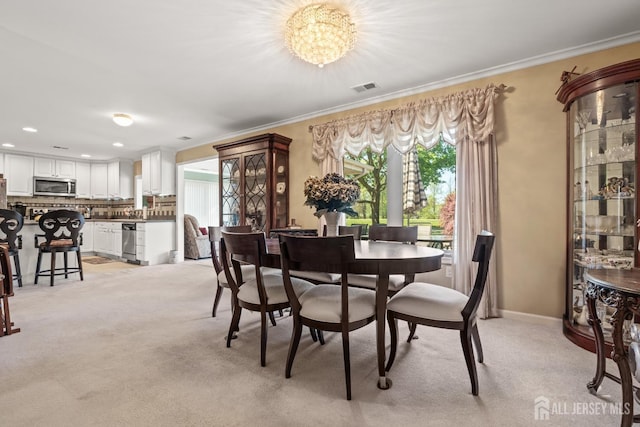dining room with ornamental molding, light colored carpet, and recessed lighting