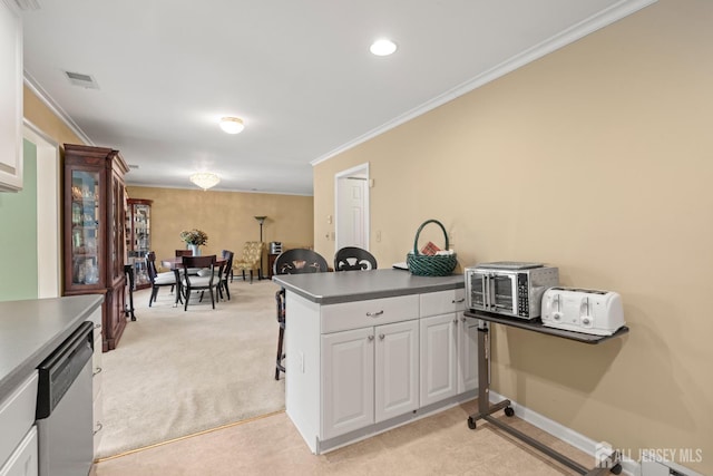 kitchen featuring crown molding, a peninsula, stainless steel dishwasher, white cabinets, and a kitchen breakfast bar