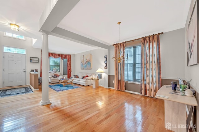 entrance foyer with light wood-type flooring, decorative columns, and plenty of natural light