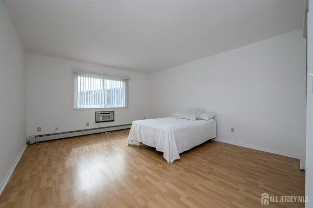 bedroom with a baseboard heating unit, light wood-style flooring, an AC wall unit, and baseboards