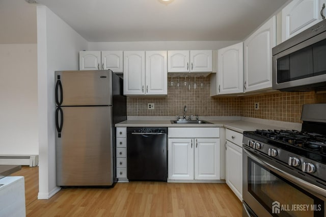 kitchen featuring stainless steel appliances, a sink, light wood-style floors, baseboard heating, and white cabinets