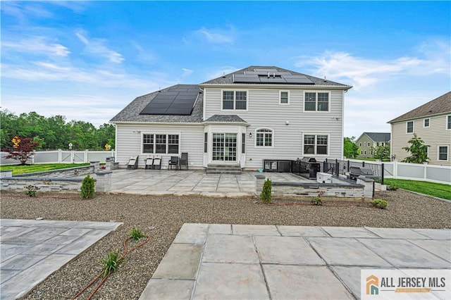 153 Scarborough Rd, Montgomery, NJ 08502 - rear view of house with entry steps, a patio, roof mounted solar panels, a fenced backyard, and a garden