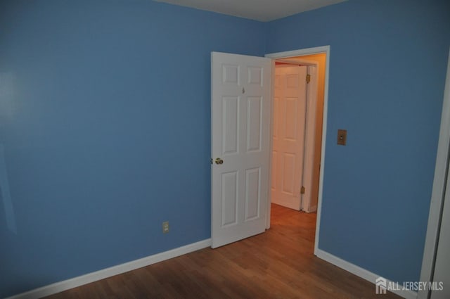 unfurnished room with wood finished floors and baseboards