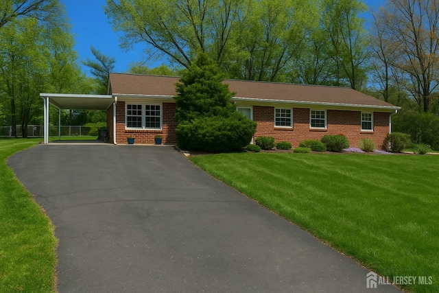 single story home featuring brick siding, driveway, a front yard, and an attached carport