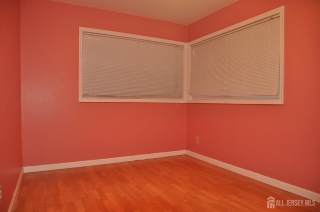 unfurnished room with baseboards and wood finished floors
