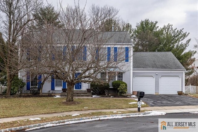 colonial house featuring a front lawn and a garage