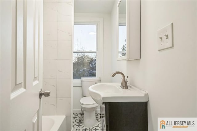 bathroom featuring tile patterned flooring, vanity, toilet, and a tub to relax in