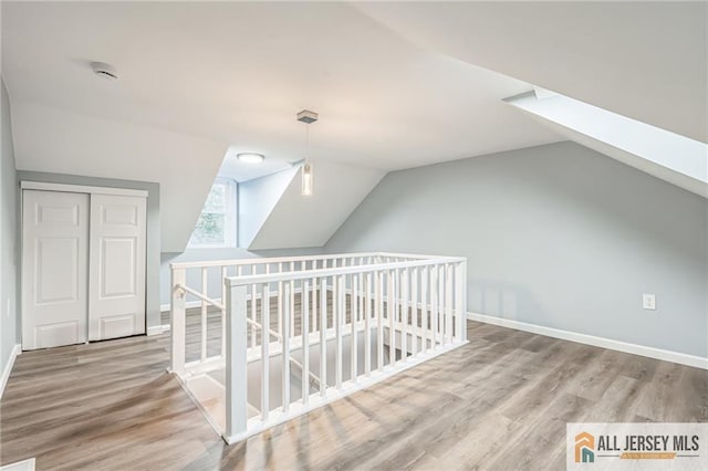 additional living space featuring light wood-type flooring and vaulted ceiling