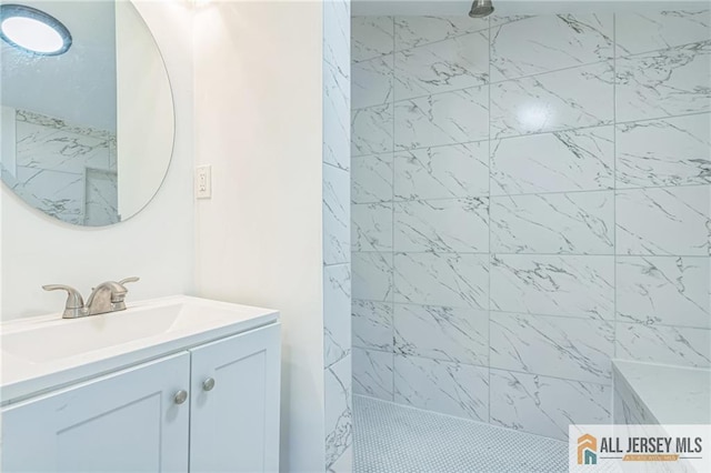 bathroom with a tile shower and vanity