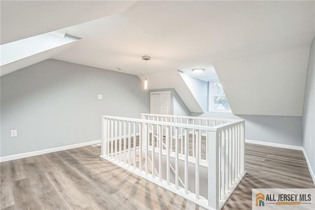 bonus room with lofted ceiling with skylight and wood-type flooring